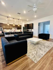 a living room with black couches and a kitchen at Spacious 6 Bedroom Home- Near Historic McKinney in Melissa