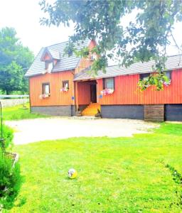 a red house with a lawn in front of it at Etno wooden room in Rakovica +4 photos