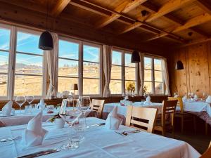 a restaurant with white tables and chairs and windows at Oberraut in Brunico
