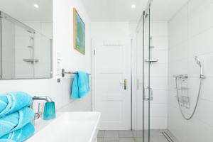 a bathroom with a sink and a shower with blue towels at Haus Delphin in Juist +61 photos