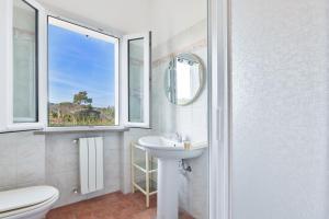 Un baño con lavabo, inodoro y ventana. en Appartamenti Le Prade - Goelba, en Portoferraio