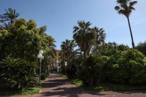 a street with palm trees and a house in the distance at Villa Giglio in Bordighera