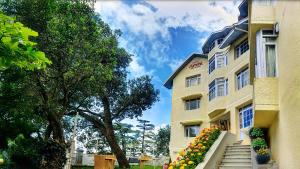 西姆拉Summit Le Royale Hotel, Shimla的一座黄色的建筑,在台阶上种着鲜花