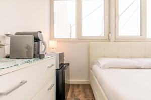 セトゥーバルにあるGuestReady - Casa e Estúdio Azeitãoの白いベッドルーム(ベッド1台、窓2つ付)