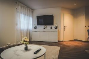 a living room with a flat screen tv on a wall at Moderne Ferienwohnung mit Kochinsel in Sinsheim Zentral ruhig und Netflix - Erstbezug WeHome Komfort in Sinsheim