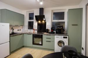 eine Küche mit grünen Schränken und einer Waschmaschine in der Unterkunft 2 Bedroom, 1 Bathroom apartment in Blackpool + 3 Fotos