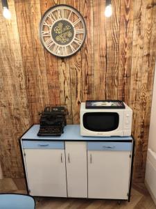 a kitchen with a microwave and a clock on a wall at Appartement Place des Eaux Bonnes in Eaux-Bonnes