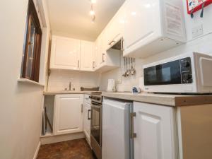 Una cocina con gabinetes blancos y un microondas. en Mousehole Bungalow, en Penzance 8 fotos más