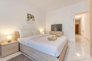 una camera da letto con un grande letto bianco e una televisione di New Studio in Msida a Msida