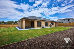 a small house with a yard with a grass at KozyGuru Pakenham Comfortable 4-Bedroom House in Pakenham