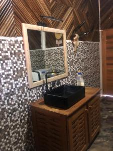 a bathroom with a black sink and a mirror at STYLE MALGACHE et TOUT CONFORT in Nosy Be
