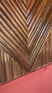 a wooden ceiling in a room with a pink wall at STYLE MALGACHE et TOUT CONFORT in Nosy Be