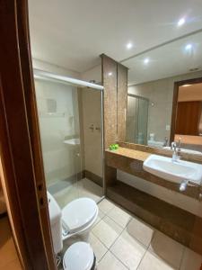 a bathroom with a toilet and a sink and a mirror at Mirador Praia Hotel in Natal