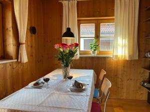 a table with a vase of flowers and two glasses of wine at Häuschen Kunterbunt in Mittenwald