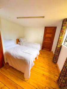 a bedroom with two beds and a wooden floor at Ol eburru cottage budget rooms in Gilgil