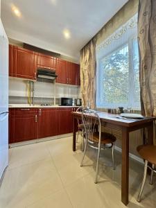 una cucina con tavolo in legno e finestra di ApartPoltava Світлі та стильні апартаменти в центрі Полтави біля театру Гоголя, ЦУМ, банківський ЧЕК a Poltava