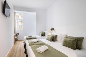 a white bedroom with two beds with green pillows at htop BCN City #htopEnjoy in Barcelona