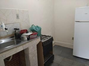 La cuisine est équipée d'une cuisinière, d'un évier et d'un réfrigérateur. dans l'établissement Casa no Centro de Tinguá, à Nova Iguaçu