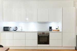a white kitchen with white cabinets and appliances at Stunning 2 BR Home on Nyhavn with Private Balcony in Copenhagen