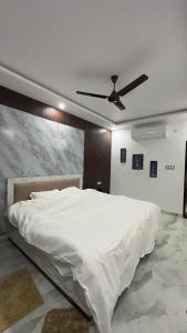 a bedroom with a white bed with a ceiling fan at Sapphire By the Ganges in Prayagraj