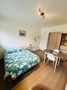 Un dormitorio con una cama, un escritorio y una mesa. en Le Petit Gambetta, en Charleville-Mézières