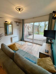 a living room with a couch and a tv at Au Ch'ti Cosy in Roubaix