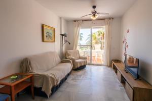 Una sala de estar con un sofá y un televisor. en Costa Ballena - Apt para 6 con piscina, terraza, WiFi y parking gratis, en Rota