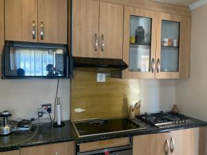 a kitchen with wooden cabinets and a sink and a stove at Khosana travel and tours in Pimville