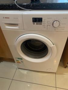 a white washing machine sitting on a kitchen floor at Khosana travel and tours in Pimville +4 photos