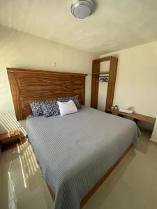 a bedroom with a large bed with a wooden headboard at Casa de huéspedes a solo 10 minutos la Playa in Playa del Carmen