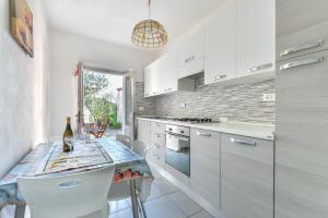 a kitchen with white cabinets and a table with chairs at Casa Gaia direttamente sul mare in Pomonte