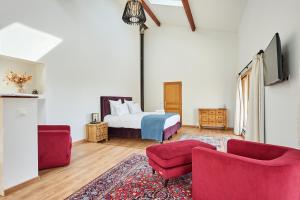 - une chambre avec un lit et deux chaises rouges dans l'établissement Domaine de Badine, 15 min Bordeaux & Saint-Emilion, à Saint-Sulpice-et-Cameyrac