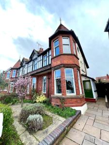 ein großes Backsteinhaus mit einem Gambrel in der Unterkunft The 100 House - Llandudno in Llandudno