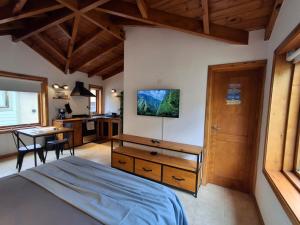 a bedroom with a bed and a desk and a kitchen at Joli Apartments - Studio 12 in San Martín de los Andes