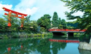 a red bridge over a river with trees and a river at "NAGOMI"Kyoto Okazaki 京都岡崎の町家 和 in Kyoto