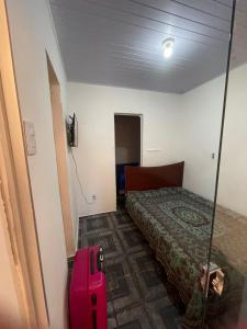 Zimmer mit einem Bett und einem rosa Koffer in der Unterkunft Casa avenida Sílvio Felício in Diamantina + 5 Fotos