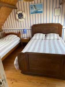 two beds in a room with striped walls at L'Anse de Landemer Montfarville in Montfarville