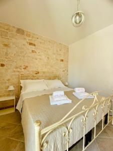 ein weißes Bett in einem Zimmer mit Ziegelwand in der Unterkunft Rifugio Rosa in Castellana Grotte