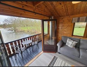 a porch with a couch and a table and chairs at Filby Broads Lodge Houseboat in Norwich