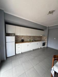 une cuisine vide avec des armoires et des appareils blancs dans l'établissement Sunshine summer house, à Paralia Dionisiou