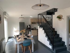 a dining room with a table and a staircase at Hébergement Guer in Guer