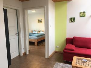 Una sala de estar con un sofá rojo y una cama. en Ferienwohnung Turmblick, en Marienrachdorf