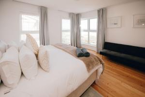a bedroom with a large white bed with two windows at Thyme & Tide Beach Villa in Yzerfontein +105 photos