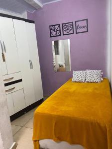 - une chambre avec un lit jaune et un mur violet dans l'établissement Kitnet Diamantina, à Diamantina