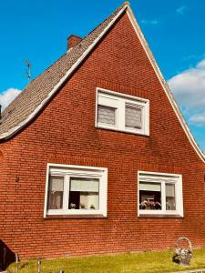 a red brick house with three windows on it at Ferienwohnung mit Seeblick in Jemgum