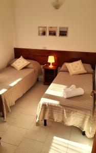 due letti in una stanza d'albergo con asciugamani sopra di Ferienhaus Casa Limone - Villaggio Galanu a Costa Paradiso