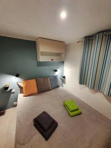 a bedroom with a large bed with green towels on it at Campingland Ostsee - Mobilheim A1Seestern in Schashagen