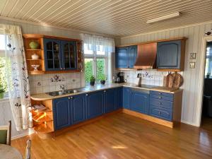 a kitchen with blue cabinets and a wooden floor at Stort hus på Fen i Ulefoss i rolige omgivelser in Ulefoss