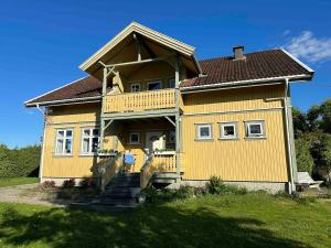 a yellow house with a balcony on a yard at Stort hus på Fen i Ulefoss i rolige omgivelser in Ulefoss