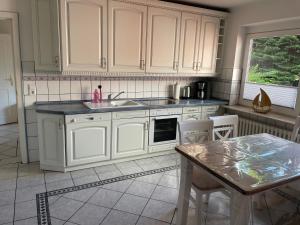 a kitchen with white cabinets and a table at Ferienhaus Osterende in Bordelum +9 photos